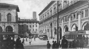 Piazza Uccelli si trovava tra il lato orientale di Palazzo del Podestà e il portico di Palazzo dei Banchi. Dietro si intravede la torre Lambertini ed i i merli restaurati del Palazzo del Podestà. Gli stabili che si trovavano tra questa piazza e via Rizzoli (isolati che comprendevano via Accuse e via Spaderie) furono definitivamente abbattuti nel 1913.