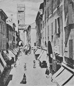 Via degli Orefici come era prima del 1911, anno in cui iniziarono gli abbattimenti che avrebbero interessato la parte visibile a destra. L'arco ben visiile sulla destra è il voltone di via Cimarie. L'edificio sporgente poco più avanti era l'Albergo del Commercio, già del Leoncino. Pare che in quel palazzo abbia abitato Francesco Raibolini detto il Francia