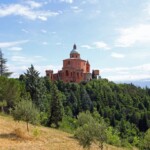 La basilica vista dalla via di San Luca, nei pressi del parcheggio. Da notare l'edificio dell'acquedotto ed il piccolo campanile (resto della chiesa del 1696) dotato di cuspide (costruita alla fine del XIX secolo).