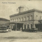 Tram, carrozze a cavalli e una autovettura davanti alla Stazione.